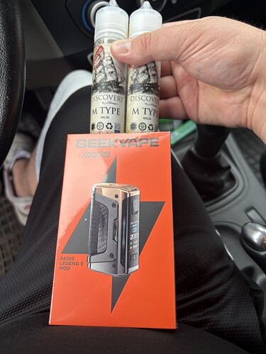 A person holds two bottles of e-liquid and a box of a Geekvape vaping device. (Subtitled with AI)