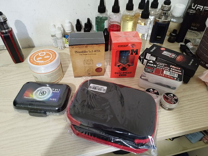 Various vaping-related products, including RDAs, flavors, and other accessories, are visible on the table. (Labeled by AI)
