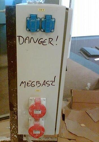 Une inscription sur l'armoire électrique avertit du danger et contient un langage grossier en langue hongroise. (Sous-titré par IA)