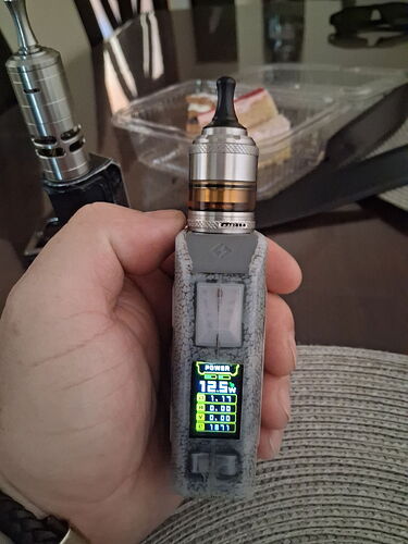 An e-cigarette device held in a hand is visible, with various settings and values displayed on its screen. (AI-generated caption)