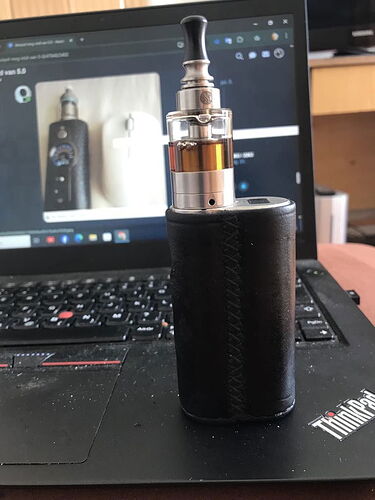 On the desk, a black leather-covered e-cigarette stands in front of a ThinkPad laptop keyboard, on whose screen the same device is visible. (Subtitled by AI)