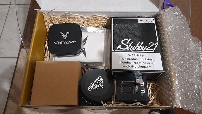 Various e-cigarette products and accessories from different brands are placed in a cardboard box. (captioned by AI)