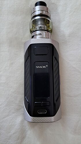 L'image représente une cigarette électronique (vape) moderne de marque SMOK, de couleur noir et argent, sur fond blanc. (Légendé par IA)