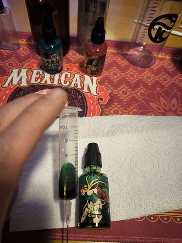 The image shows a pipette and bottles containing various flavored liquids, with paper towels on the table. (Captioned by AI)