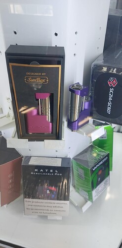 L'image montre divers produits de vapotage exposés dans un magasin, y compris un mod de vapoteuse violet et rose conçu par SunBox. (Légendé par IA)