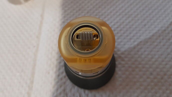 The image is a close-up, top-down photo of an electronic cigarette's coil area. (Subtitled by AI)