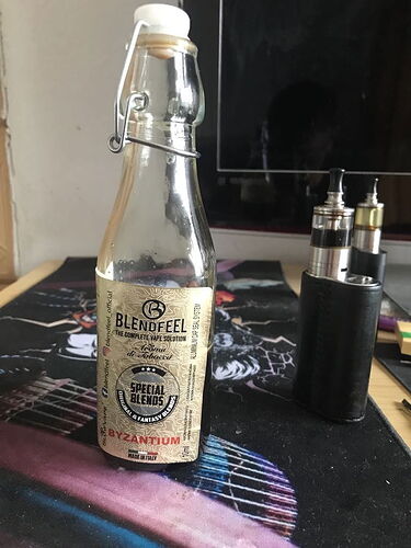 An empty Blendfeel e-liquid bottle and two electronic cigarette (vape) devices are visible on the table. (Subtitled with AI)