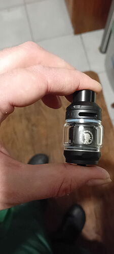 A hand holds a small, black and clear tank with a lion logo on it. (Labeled by AI)