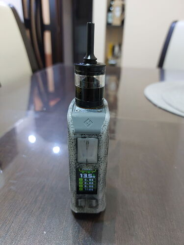 A vape device is shown standing on a shiny surface. (Labeled by AI)
