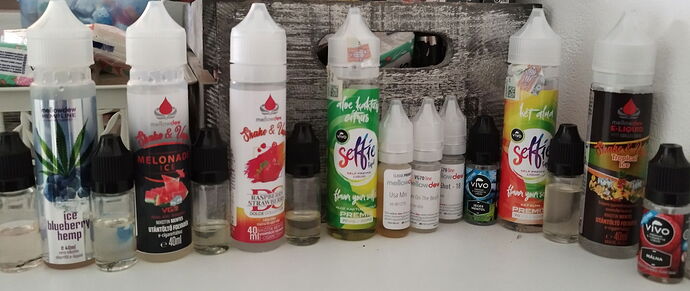 Bouteilles d'eliquides de différentes saveurs et flacons de recharge sont alignés côte à côte sur la table. (Légendé par IA)