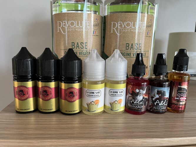 The image shows bottles of e-liquid in various flavors, as well as two larger bottles of base material. (Labeled by AI)