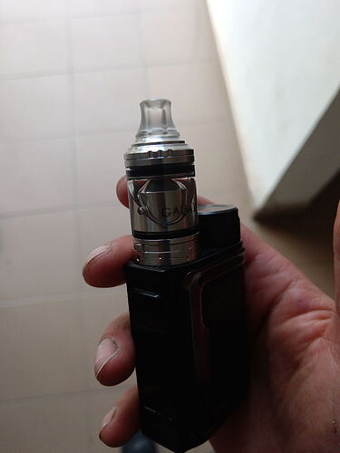 A hand holds a black electronic smoking device (vape), of which the metal and glass parts are clearly visible. (Labeled by AI)