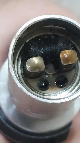 This image shows a metal connector with a buildup of black and brown material inside. (Captioned by AI)
