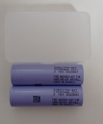 In the picture, two purple INR21700-40T batteries are visible, placed over a white plastic case. (Captioned by AI)