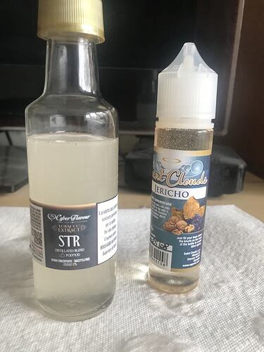 Deux flacons de concentré de liquide côte à côte sur une serviette en papier blanche, l'un des flacons porte l'inscription Cyber Flavour STR, l'autre étiquette Silent Clouds Jericho. (Sous-titré par IA)