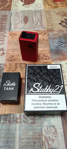 The image shows a red e-cigarette device, a Stubby TANK box, and a Stubby 21 box, which features a smoking-related warning. (Subtitled by AI)