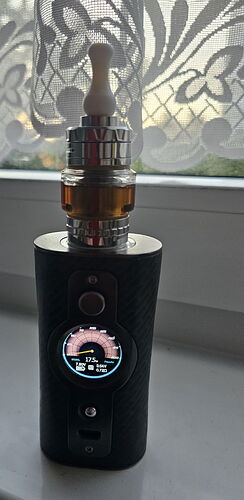 A black vaporizer device is visible on a windowsill, with a lace curtain and sunset in the background. (Caption by AI)