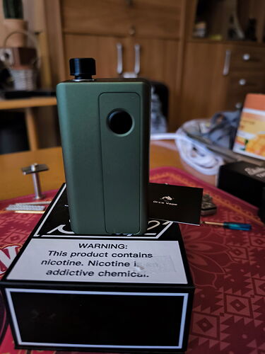 A green vaporizer is shown in the image, placed on a box with a warning label. (Autogenerated by AI)