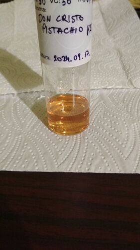 The liquid in the glass bottle is yellowish-orange, with a label reading "DON CRISTO PISTACHIO" and an expiration date of 2024.09.17. (AI-captioned)