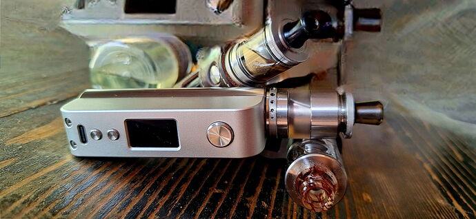 An electronic cigarette or vape device made of metal and glass parts is visible in a close-up view. (captioned by AI)