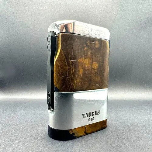 Cette image représente un briquet de poche décoré de métal et de bois, portant l'inscription "TAURUS 046". (Légendé par IA)