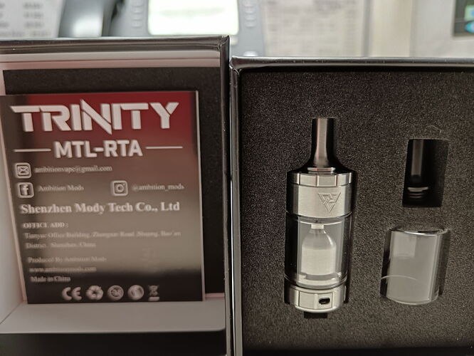 Un kit atomiseur TRINITY MTL-RTA et sa boîte sont visibles sur l'image. (Légendé par IA)