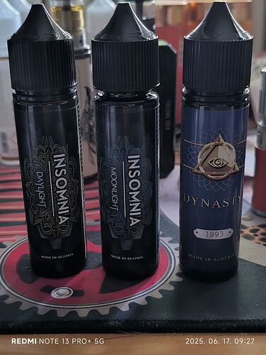 Trois bouteilles noires en plastique alignées côte à côte, sur lesquelles on peut lire les noms de marque "INSOMNIA" et "DYNASTY". (Légendé par IA)