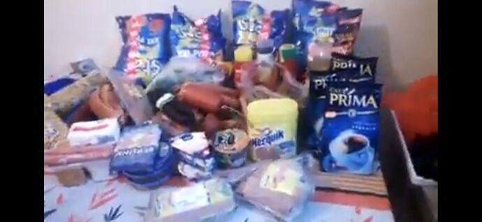 Various food items such as coffee, sausages, sugar, spices, and snacks are placed on the table. (Labeled by AI)