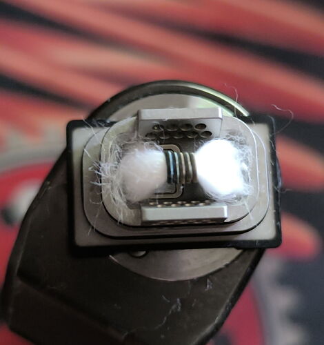 The picture shows the coil and cotton of an e-cigarette atomizer under a transparent cover. (Captioned by AI)