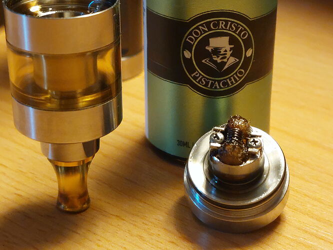 In the picture, an e-cigarette (vape) tank, a bottle of flavor liquid, and a coil are visible. (Labeled by AI)