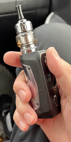 Une main tient une cigarette électronique noire Geek Vape. (Légendé par l'IA)