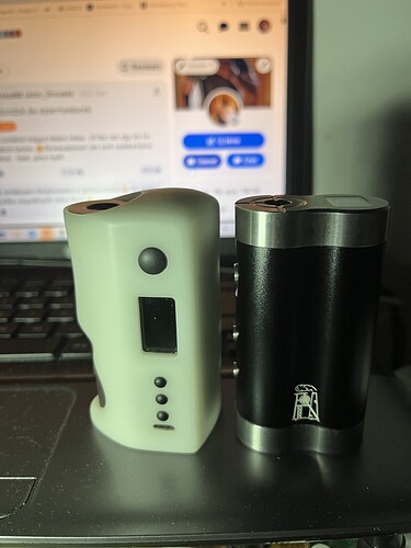 Two black and white electronic devices of different sizes and shapes are visible in front of a laptop keyboard. (AI-generated caption)