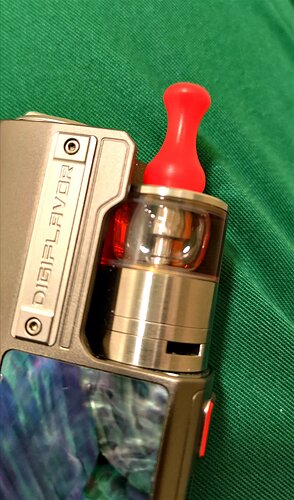 Ez a kép egy digitális e-cigarettát ábrázol piros szilikon szájrésszel, zöld háttér előtt. (Feliratozva AI-val)