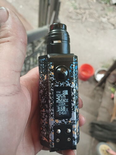 A person is holding a black and white patterned electric cigarette (vape) with a digital display, showing various settings. (Subtitled by AI)