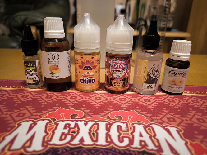La photo montre différentes substances liquides aromatisées destinées à l'usage de la vape, disposées sur un sous-verre à motif mexicain. (Légendé par IA)