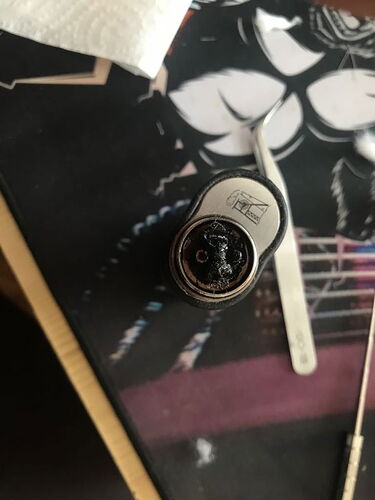 In the picture, a burnt or damaged microphone windscreen is visible on a table, next to which a tweezers also lies. (Subtitled with AI)