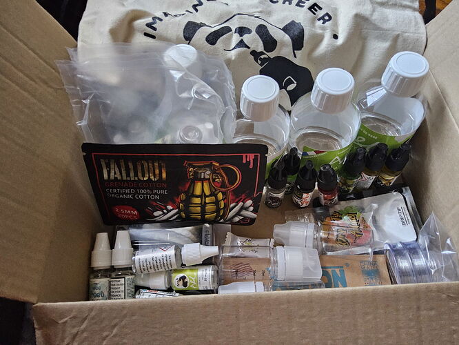 A cardboard box containing various e-cigarette liquids, bottles, and a package of granular material. (Caption by AI)