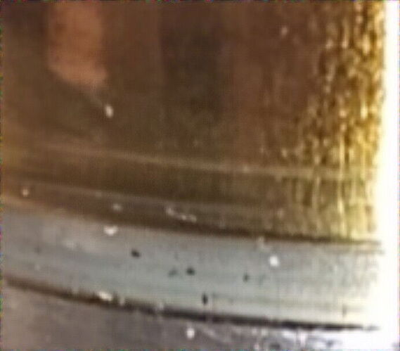 The image shows an old, worn, and dirty metal or ceramic surface. (captioned by AI)