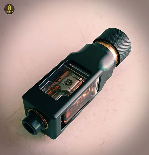 L'image montre un appareil de cigarette électronique (vape) moderne composé de pièces métalliques et en plastique avec un panneau latéral transparent. (Légendé par IA)