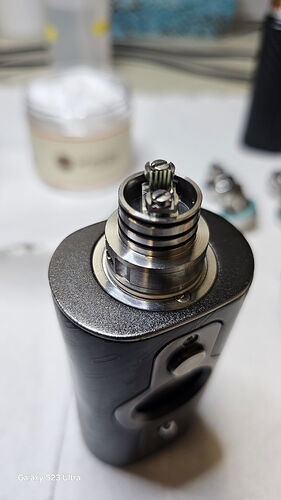 L'image est un gros plan d'un mod de vape électronique, montrant une bobine et une partie de support en coton. (Légendé par l'IA)