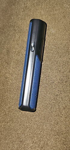 A black and blue device with one button is visible in the image. (Subtitled by AI)