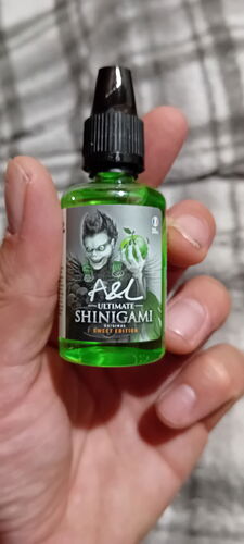 Une main tenant un liquide vert nommé A&L Ultimate Shinigami Sweet Edition dans une bouteille en plastique avec un compte-gouttes, dont l'étiquette représente le portrait d'un personnage. (Traduit automatiquement par IA)