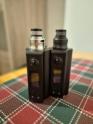 Two vape devices with different designs are visible on a Christmas-patterned tablecloth. (Captioned with AI)