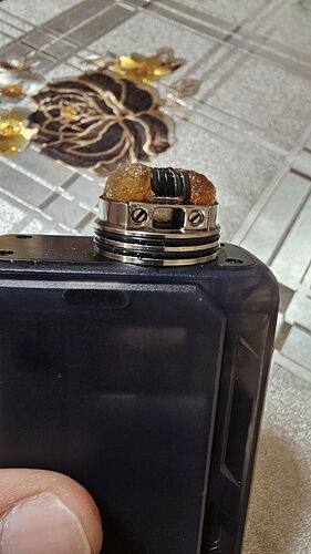 Egy black box előterében egy porlasztó rész látható, melyben beszívott és elhasznált wick és coil található. (Feliratozva AI-val)