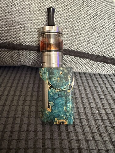 L'image montre un appareil de vapotage coloré avec un revêtement en résine et un réservoir métallique. (Légendé par IA)