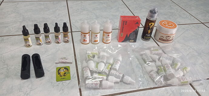 Az asztalon különféle e-liquid palackok, tartozékok és csomagolt termékek vannak szétterítve. (Feliratozva AI-val)