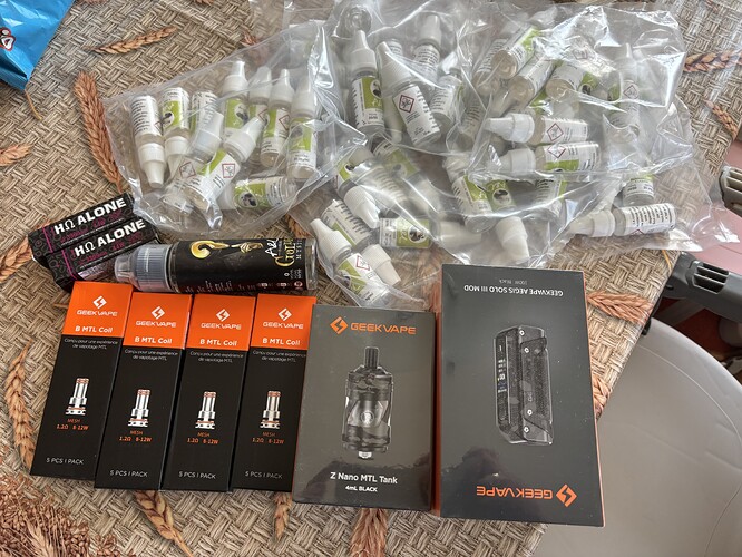 Several packs of vaporizer cartridges and smoking devices, as well as various blurred bags are placed on the table. (Subtitled by AI)