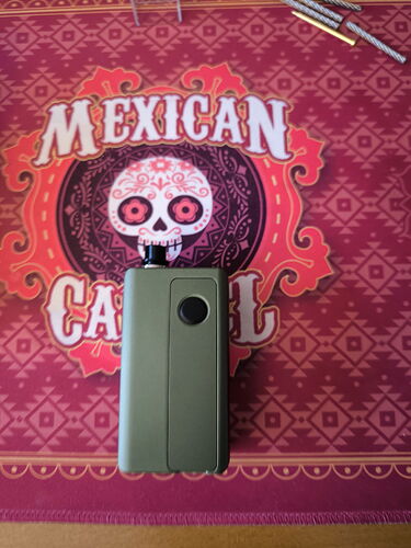 The image depicts a green device placed on a red and pink background with Mexican motifs. (Autogenerated by AI)