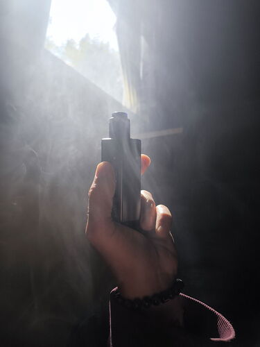 A hand holds a pistol while smoke and light penetrate the background. (Subtitled by AI)