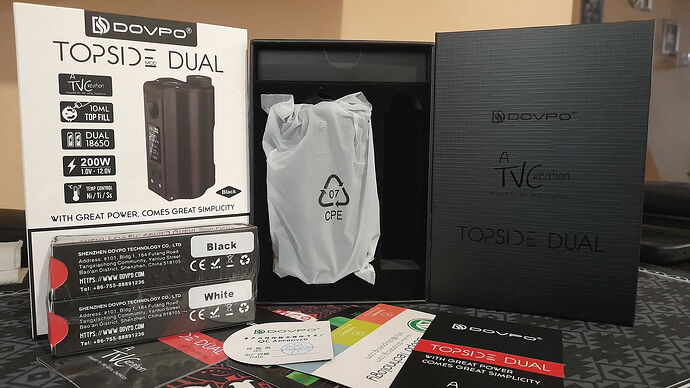 L'image représente un kit de cigarette électronique Dovpo Topside Dual, comprenant des boîtes, le mod, ainsi que des manuels d'utilisation et d'autres accessoires. (Légendé par IA)